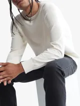 Sweater de punto liso color blanco, con cuello redondo y puños y dobladillo en punto canalé.