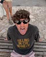 Remera oversize color beige con efecto acid wash y estampa frontal en marrón con la frase "Killing In The Name Of".