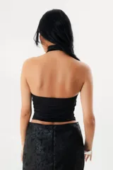 Top halter negro de microfibra, con detalle de tira larga al cuello estilo corbatero y diseño ajustado a la silueta con espalda descubierta.