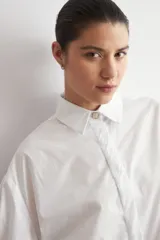 Camisa de corte oversized, color blanco, con cuello clásico, cierre frontal de botones y mangas largas.