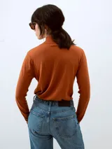 Sweater de punto color ladrillo, con cuello alto y mangas largas.