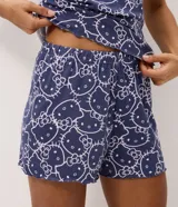Pijama short doll de dos piezas en color azul marino con estampa integral de Hello Kitty en tono claro. Consta de una musculosa de tirantes finos con escote en V decorado con un pequeño lazo y un short con cintura elástica.