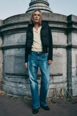 Chaqueta acolchada negra con capucha ajustable, cuerpo con aislamiento térmico y mangas largas en tejido técnico efecto neopreno. Presenta cierre frontal con cremallera, bolsillos laterales y bajo ajustable con cordones elásticos.