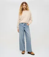 Pantalón de jean corte wide leg con cintura baja y cierre frontal con botón y cremallera. Presenta un diseño de pierna ancha y tiro bajo, confeccionado en algodón resistente con acabado en tono azul claro.