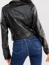 Campera estilo motoquera de símil cuero negro, con solapas amplias y detalles de tachas metálicas en solapas, hombros y mangas. Presenta cierre frontal cruzado, bolsillos con cierre y trabillas en el ruedo.