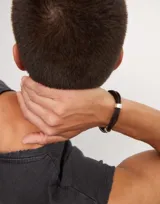 Pulsera de cuero trenzado color negro con detalles de circunferencias plateadas y cierre magnético plateado.
