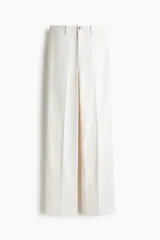 Pantalón jean de tiro alto en color blanco, con diseño de pernera recta holgada, trabillas para cinturón y cierre frontal con botón metálico. Presenta pliegues marcados al frente y bolsillos laterales.