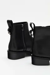 Bota corta de cuero vacuno color negro, con cierre lateral y suela de goma con detalle de tachas en el borde.