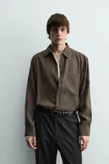 Camisa relaxed fit color verde militar, confeccionada en tejido con mezcla de modal. Tiene cuello solapa, manga larga con puño abotonado, bolsillo plastrón en el pecho y cierre frontal de botonadura.