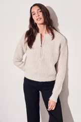 Sweater de punto color crema, con cuello redondo y cierre metálico a la mitad del frente.