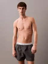 Bóxer suelto de hombre Calvin Klein, confeccionado en popelín de algodón con estampado de logos en gris y cintura elástica blanca con logo.