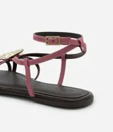 Sandalia plana color rosa con tiras finas, puntera redonda y adorno de estrella de mar dorada.