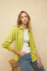 Camisa de manga larga color verde lima, con cuello y botones frontales a tono. Presenta un tejido con textura arrugada o plisada.