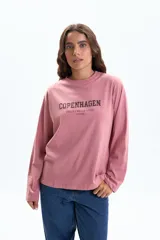 Remera de manga larga color rosa viejo, con cuello redondo y estampado frontal que dice "COPENHAGEN STREET STYLE MUSE DENMARK" en color gris oscuro.