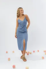 Vestido midi celeste de tejido tipo seda fría, con breteles finos regulables, botones de madera decorativos en el frente, pliegues decorativos en la cintura y cierre invisible en el costado.