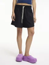 Short negro de algodón con cintura elástica y cordón de ajuste blanco. Diseño holgado y corto.