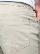 Pantalón de corte slim confeccionado en mezcla de algodón y elastano. Presenta un diseño clásico de cinco bolsillos, cierre con botón y cremallera, y detalles distintivos de la marca.
