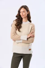 Buzo tejido de abrigo con bloques de color en tonos beige, tostado y blanco. Tiene cuello redondo, mangas largas y un pequeño parche de cuero sintético en el lateral inferior.