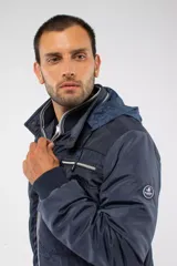 Campera de nylon color azul marino con cierre frontal completo, capucha desmontable y puños elásticos. Presenta bolsillos con cierre y logo aplicado en la manga.