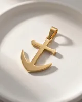Dije de acero con baño de oro en forma de ancla, con acabado pulido brillante.