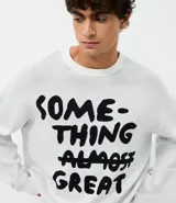 Suéter de corte boxy confeccionado en tejido jacquard de viscosa y poliéster. Presenta cuello redondo, mangas largas y un diseño estampado con lettering en color negro sobre fondo blanco.