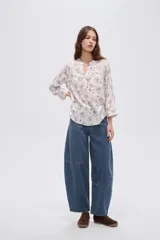 Blusa de viscosa color beige con cuello en V, cierre parcial de botones frontales, bolsillo en el pecho y mangas 3/4.