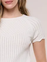 Blusa de punto calado color blanco, de silueta entallada, manga corta raglán y escote redondo, con detalles de tejido fantasía en el canesú y terminaciones festonadas.