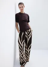 Pantalón largo de tiro medio confeccionado en viscosa fluida, con diseño recto y estampado de cebra en tonos marrón y beige. Cuenta con dos bolsillos laterales y cierre de botón.