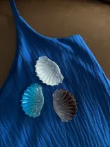 Broche con forma de concha marina en color azul, blanco y marrón.