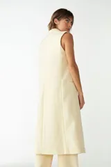 Chaleco largo marrón de lana fina sin teñir, con solapa y cierre frontal con botones.