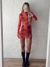 Vestido corto de microtul elastizado con estampado abstracto en tonos rojizos y anaranjados, de cuello alto y manga larga.