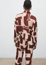Camisa de viscosa fluida con estampado geométrico en tonos marrón y beige, cuello camisero, manga larga y cierre frontal con botones.