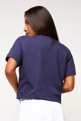 Remera blanca de algodón con corte crop, mangas cortas y estampado frontal con texto y logo en color gris.