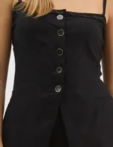 Conjunto monocromático compuesto por un top de breteles finos con escote recto y cierre frontal de botones, y un pantalón de tiro alto con pierna amplia y bolsillos laterales.