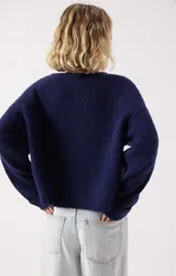 Sweater de punto fino color azul marino, con cuello redondo amplio y mangas largas con puños rectos. Presenta un corte holgado y diseño minimalista.