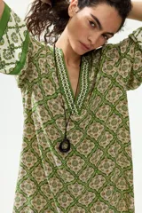 Vestido túnica corto de viscosa con estampado geométrico en tonos verdes y crudo, escote en V pronunciado tanto en el frente como en la espalda, mangas tres cuartos y diseño oversized.