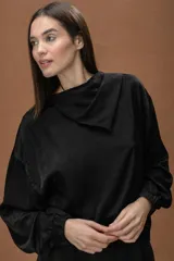 Blusa de satén color negro, con cuello drapeado, mangas largas con puños elásticos y ruedo con elástico en la cintura.