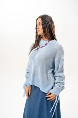 Buzo de punto celeste de silueta relajada, con mangas amplias y jaretas regulables en los puños.