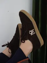 Championes de gamuza color borgoña, beige y naranja con cordones.