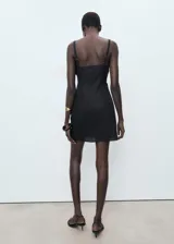 Vestido corto sin mangas de color negro, con cuello barco y diseño drapeado en la cintura. Confeccionado en una mezcla de lino y algodón con forro interior.