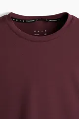 Remera deportiva de manga larga color bordó, con cuello redondo y tejido funcional con textura microperforada.