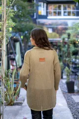 Camisa de punto calado en color beige con hilo de lurex. Presenta una silueta oversize, cuello camisero clásico, mangas 3/4 ligeramente abullonadas y cierre frontal con botones metálicos.