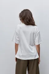 Remera de manga corta color blanco con cuello redondo y detalle de frunce lateral que aporta movimiento y una silueta entallada.