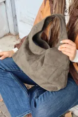 Cartera tipo hobo de gamuza negra, con diseño minimalista y asa integrada.