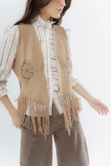 Chaleco negro de estilo boho, confeccionado en semigamuza con detalles de tejido de punto en el frente y la espalda. Presenta un diseño sin mangas con flecos en el ruedo, aportando movimiento y textura a la prenda.