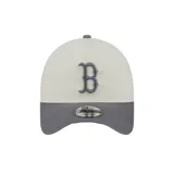 Gorra New Era modelo 9FORTY A-Frame de los Boston Red Sox, color beige con visera y botón superior grises. Cuenta con la letra 'B' bordada en el frente en relieve con contorno gris y detalles en verde lima, y el logo de la marca en el lateral.