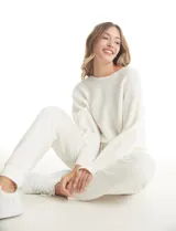 Buzo de punto acanalado horizontal en color beige, con escote a la base y diseño de manga japonesa que brinda una caída fluida y holgada.