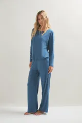 Pijama de dos piezas compuesto por una remera de manga larga con cuello redondo y un pantalón de corte recto y holgado. Ambas prendas presentan un estampado de pequeños puntos oscuros sobre una base de color azul.