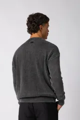 Sweater de punto grueso con textura waffle, de calce relajado y cuello redondo. Presenta puños y ruedo acanalados, con un pequeño parche con logo en el puño izquierdo.