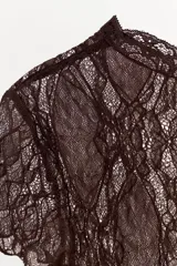 Top crop semitransparente de encaje negro, con cuello redondo y manga corta.